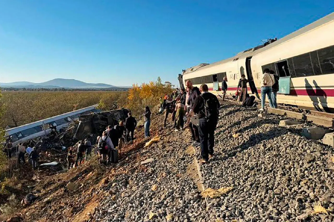 Derailed train carriages on embankment with people gathered among wreckage and rail tracks
