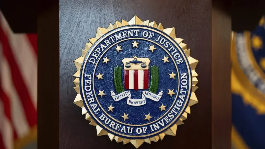 FBI seal with Department of Justice text on a dark wooden podium, flags blurred behind