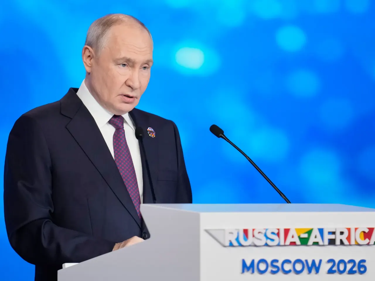 Man in dark suit speaking at podium with Russia-Africa Moscow 2026 branding on blue backdrop.