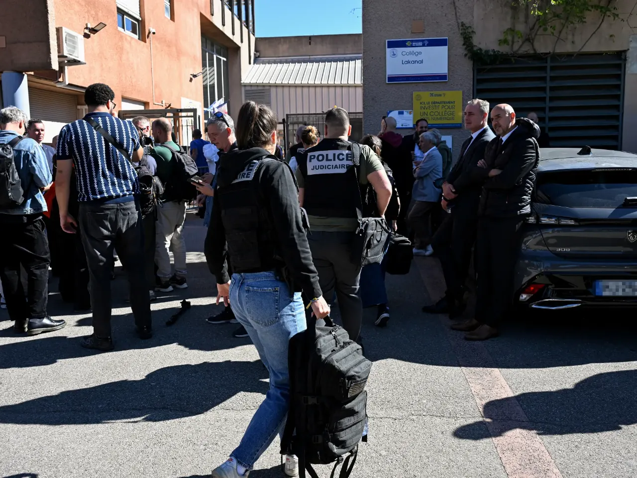 Police and officials outside the Collège Lakanal school entrance, with a judicial police officer and a black car.