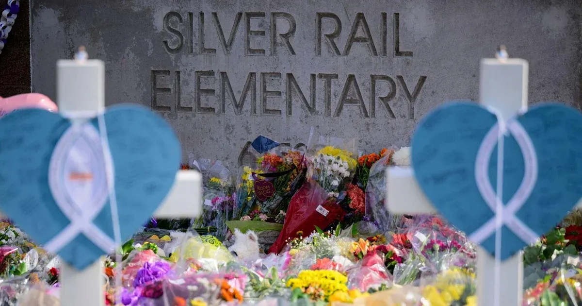 Memorial flowers and blue heart crosses in front of Silver Rail Elementary School sign