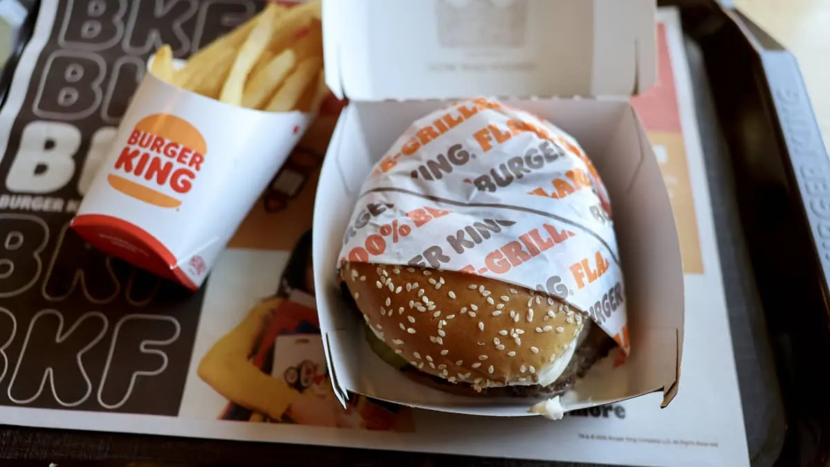 Burger King Whopper burger in box beside fries on branded tray mat