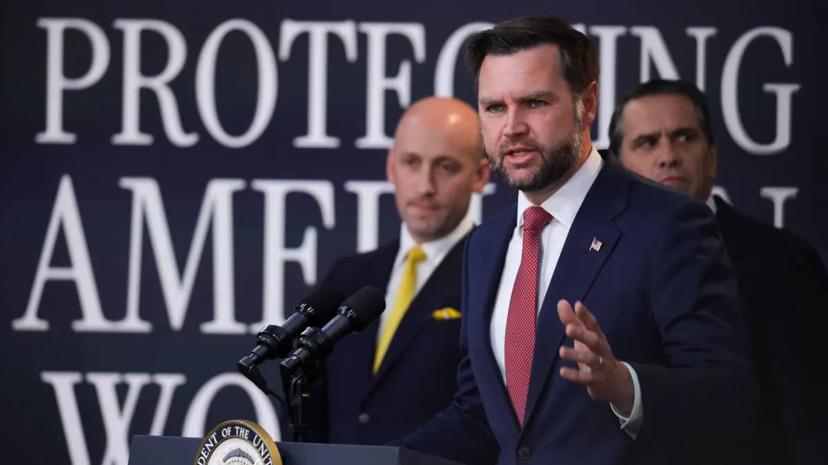 Man in dark suit speaking at podium with official seal, backdrop reading Protecting American Workers.