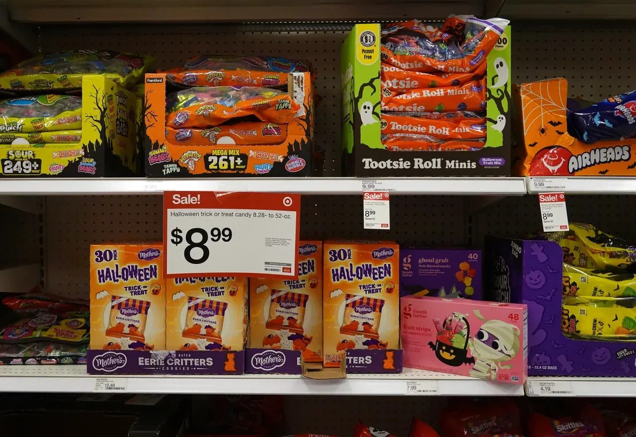 Store shelves of discounted Halloween candy with a sale price sign.
