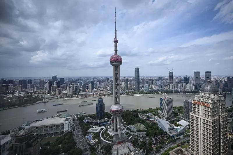 Aerial view of Shanghai skyline with Oriental Pearl Tower and Huangpu River under cloudy sky.