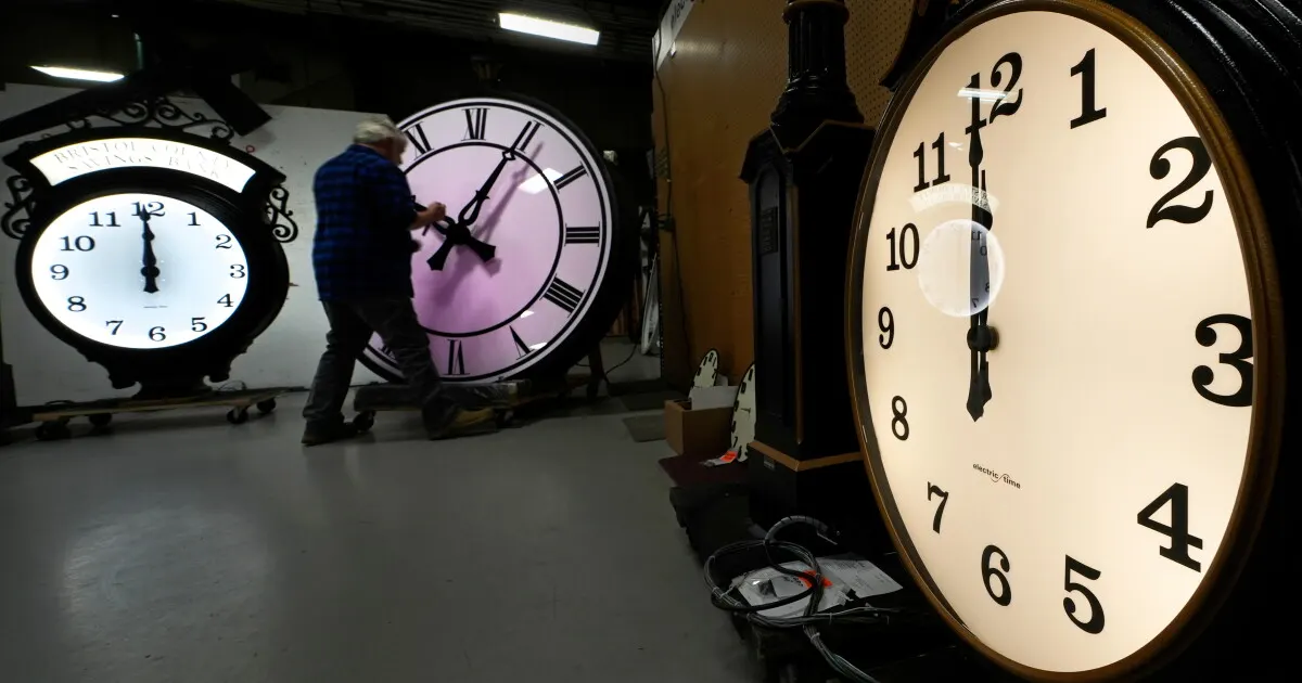 Man adjusting large clock faces in a workshop, illustrating daylight saving time changes.