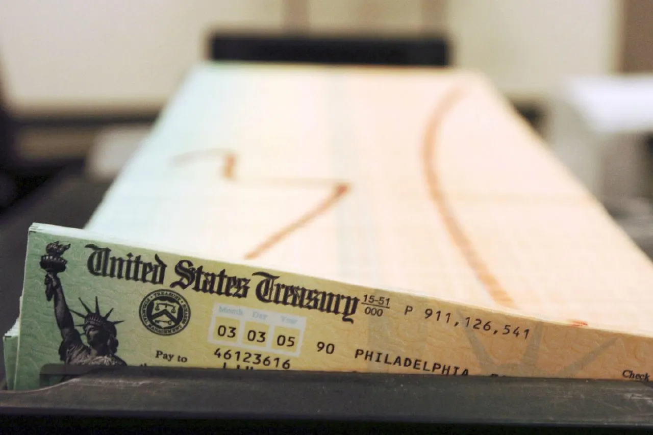 Stack of United States Treasury paper checks, Philadelphia, with Statue of Liberty seal, blurred background.