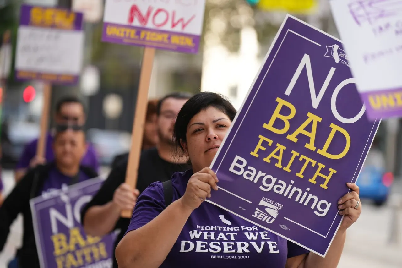 Union members marching with purple SEIU signs reading No Bad Faith Bargaining on city street