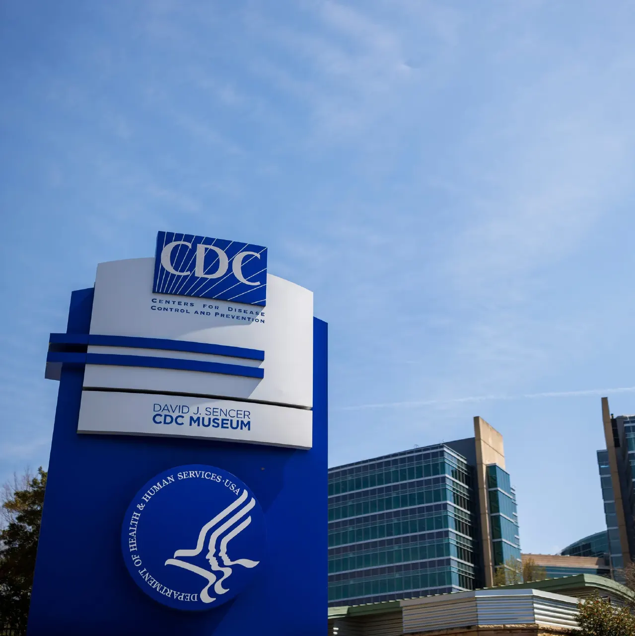 CDC Museum entrance sign with CDC and HHS logos against blue sky and buildings
