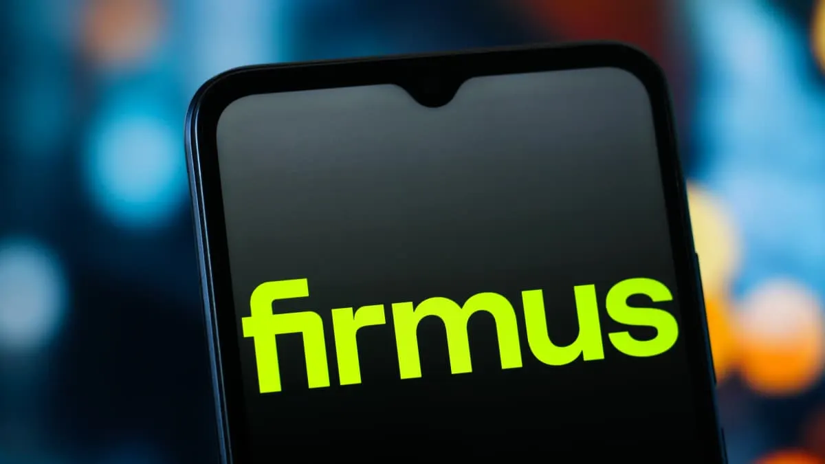 Smartphone screen displaying the green Firmus logo against a blurred blue background.