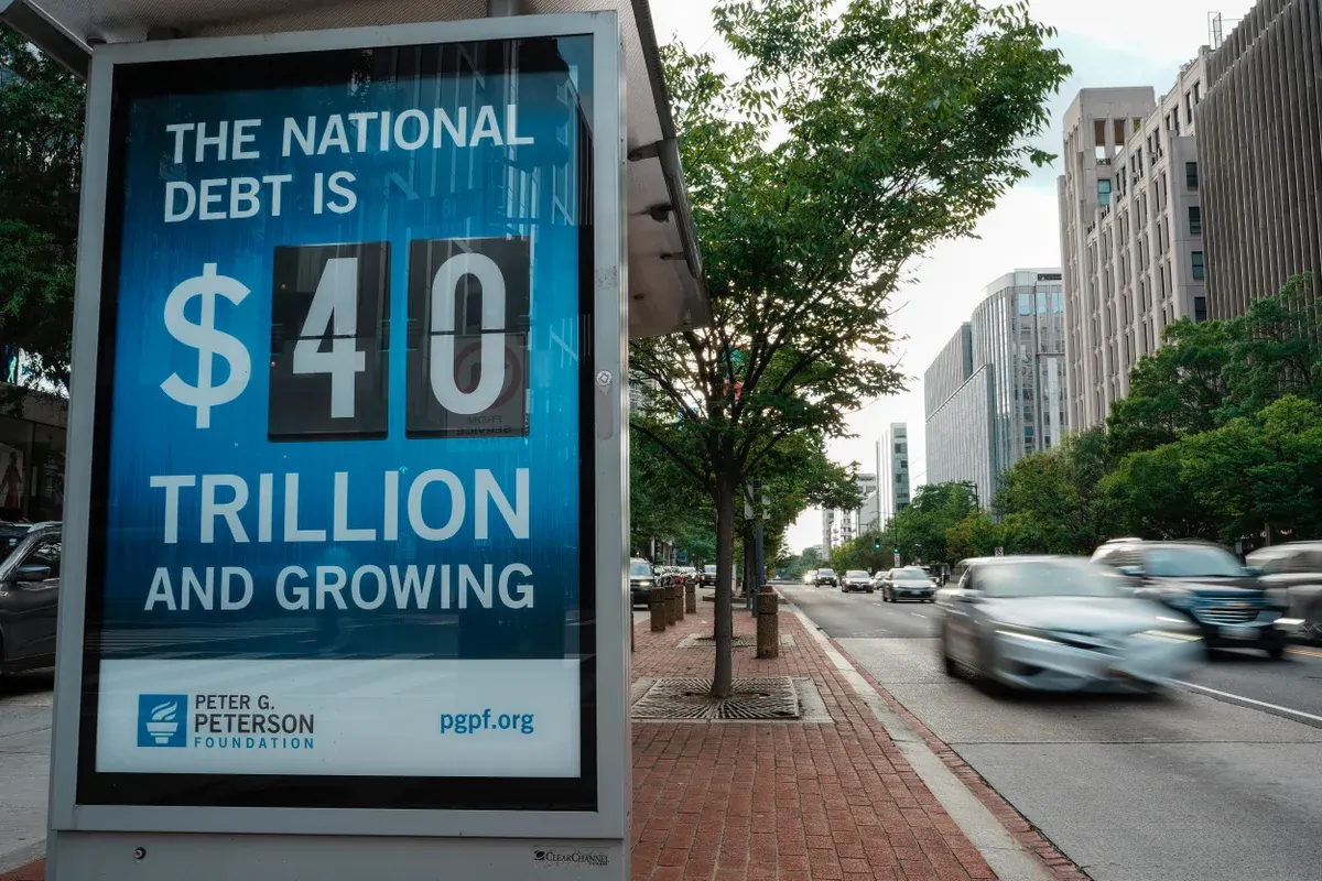 Street bus shelter ad reading national debt is $40 trillion and growing, with traffic passing