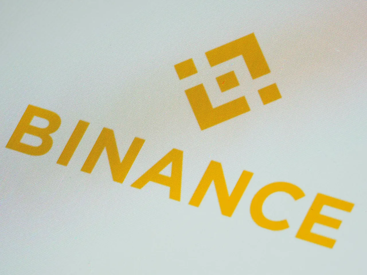 Yellow Binance logo and wordmark on a light background, shown at an angle.